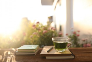 Green Tea in a glass cup and kraft paper notebook with flower background